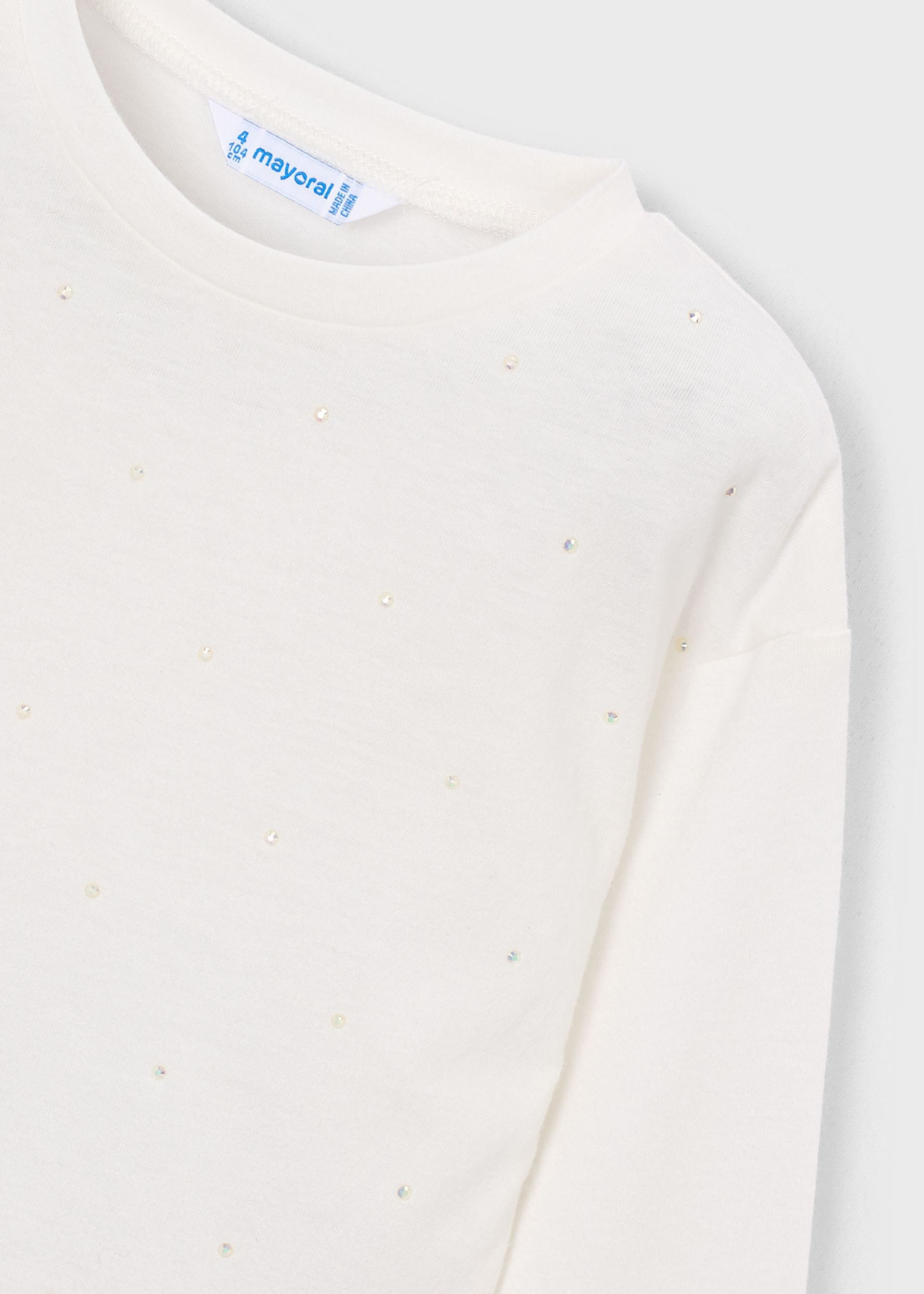 Close-up of a cream-colored long-sleeve top by Mayoral, featuring a subtle dotted pattern of small metallic studs and a visible brand label at the collar.