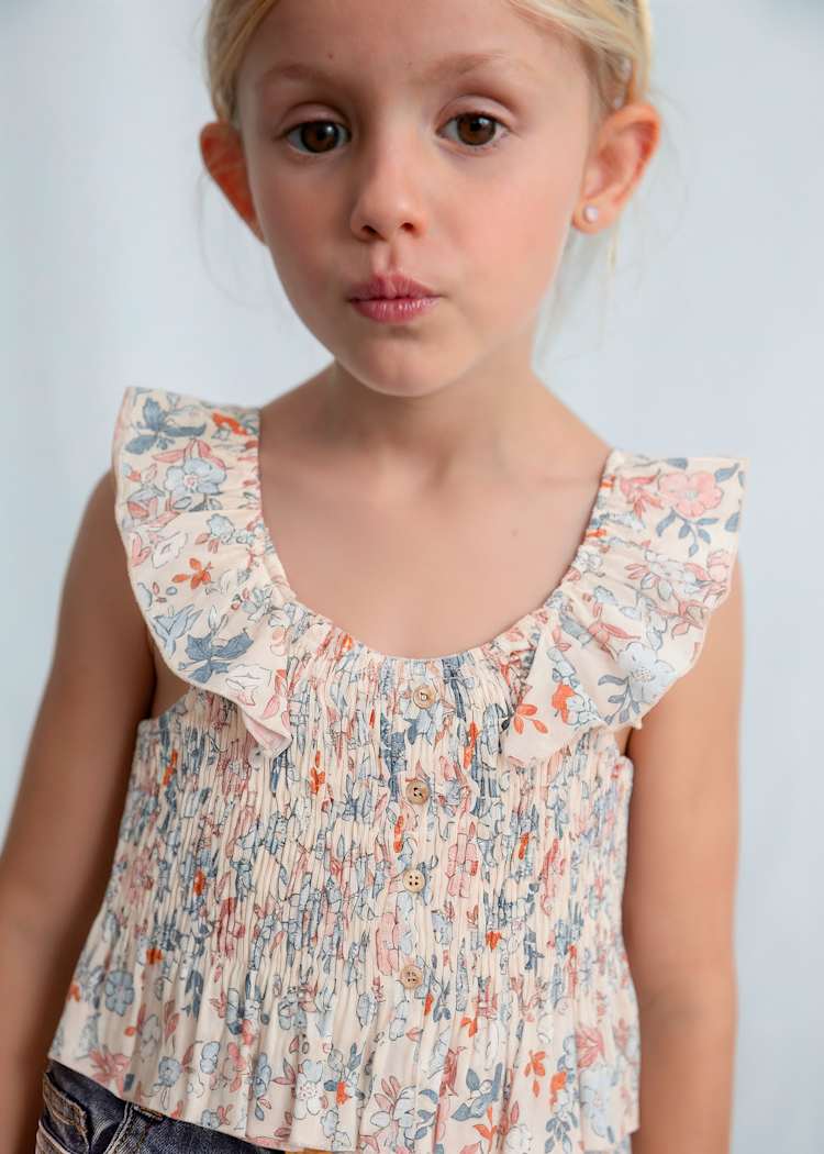 Young girl wearing a floral blouse against a plain background