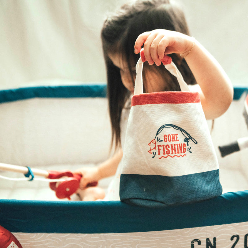 Child holding a 'Gone Fishing' bag in an indoor play area