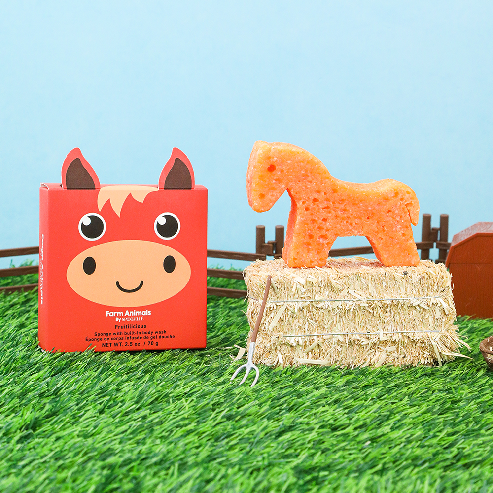 Carrot-shaped horse toy on a hay bale with a red box featuring a horse design in the background.
