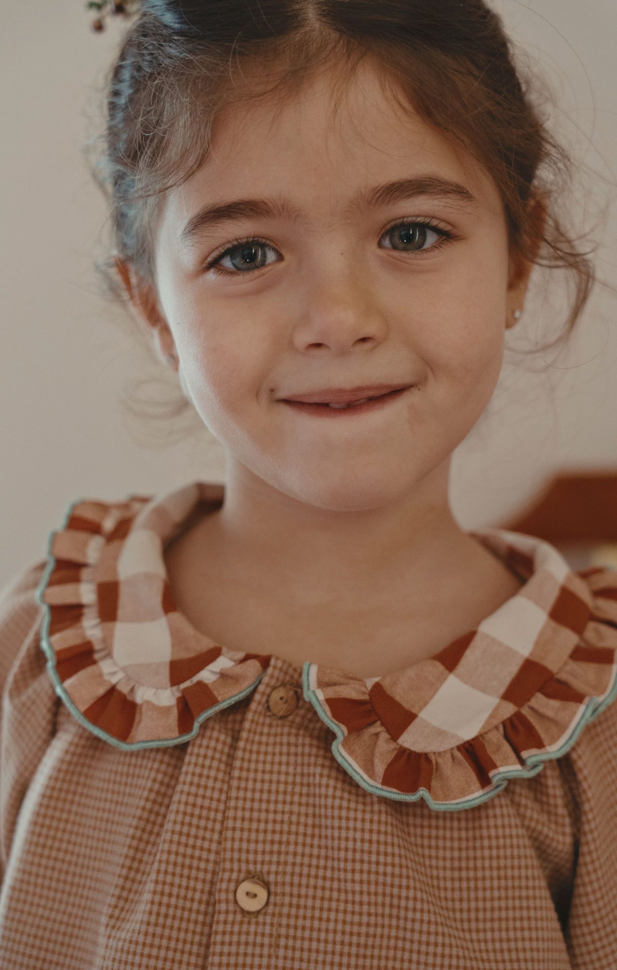 A young girl button-up shirt with a ruffled collar in brown, beige