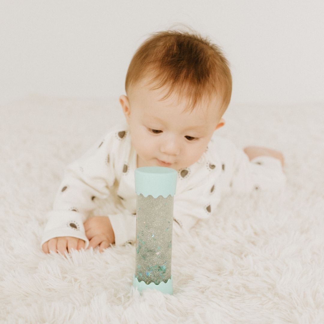 Baby sitting on a fluffy white surface with a colorful toy in front