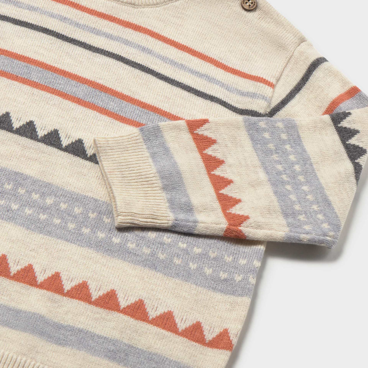 Close-up of a Mayoral sweater featuring rust-orange sawtooth bands and shoulder button fastenings.