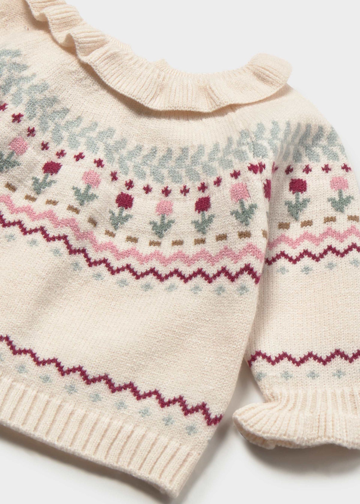 Close-up of a cream-colored knit baby sweater with a ruffled neckline and Fair Isle pattern featuring pink, burgundy, and light blue floral motifs.