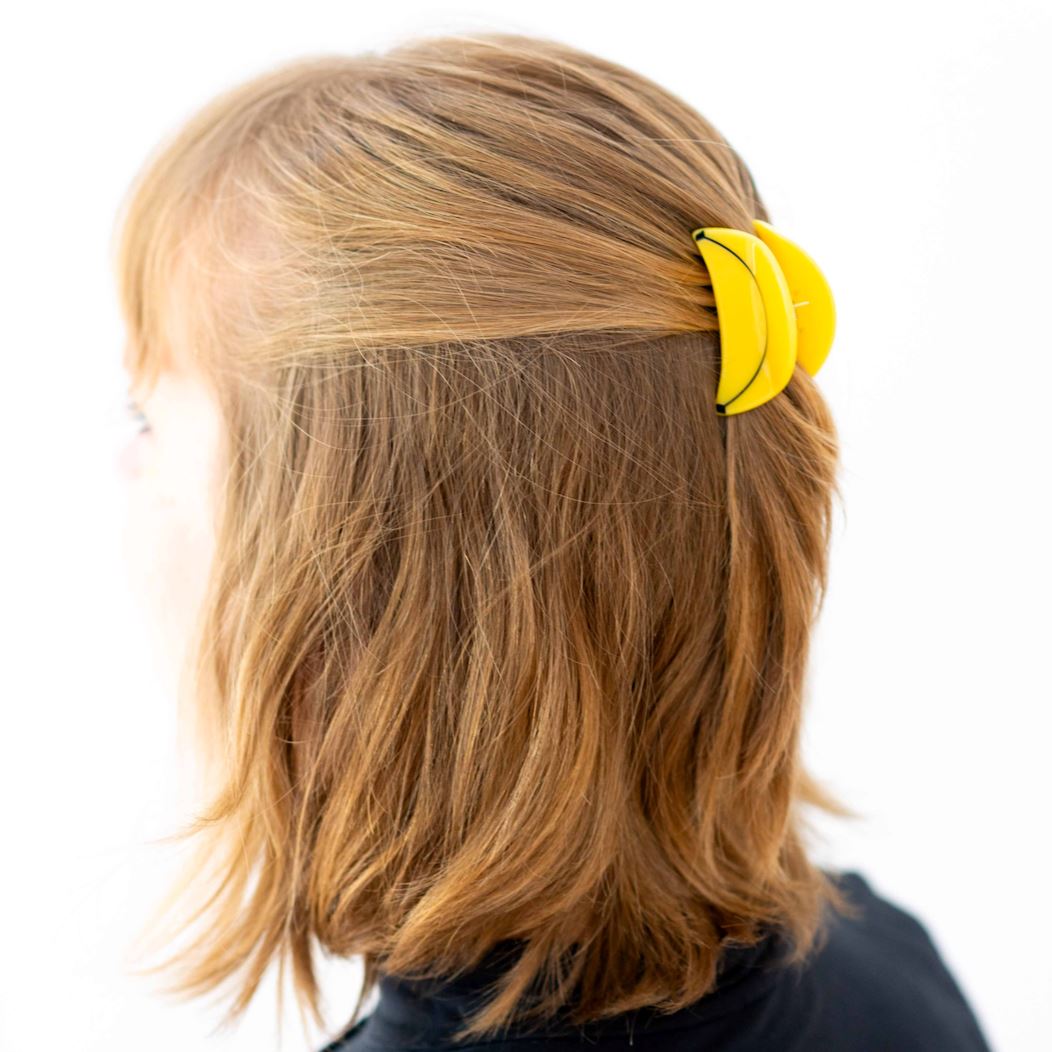 Person with a yellow hair clip in their blonde hair on a white background