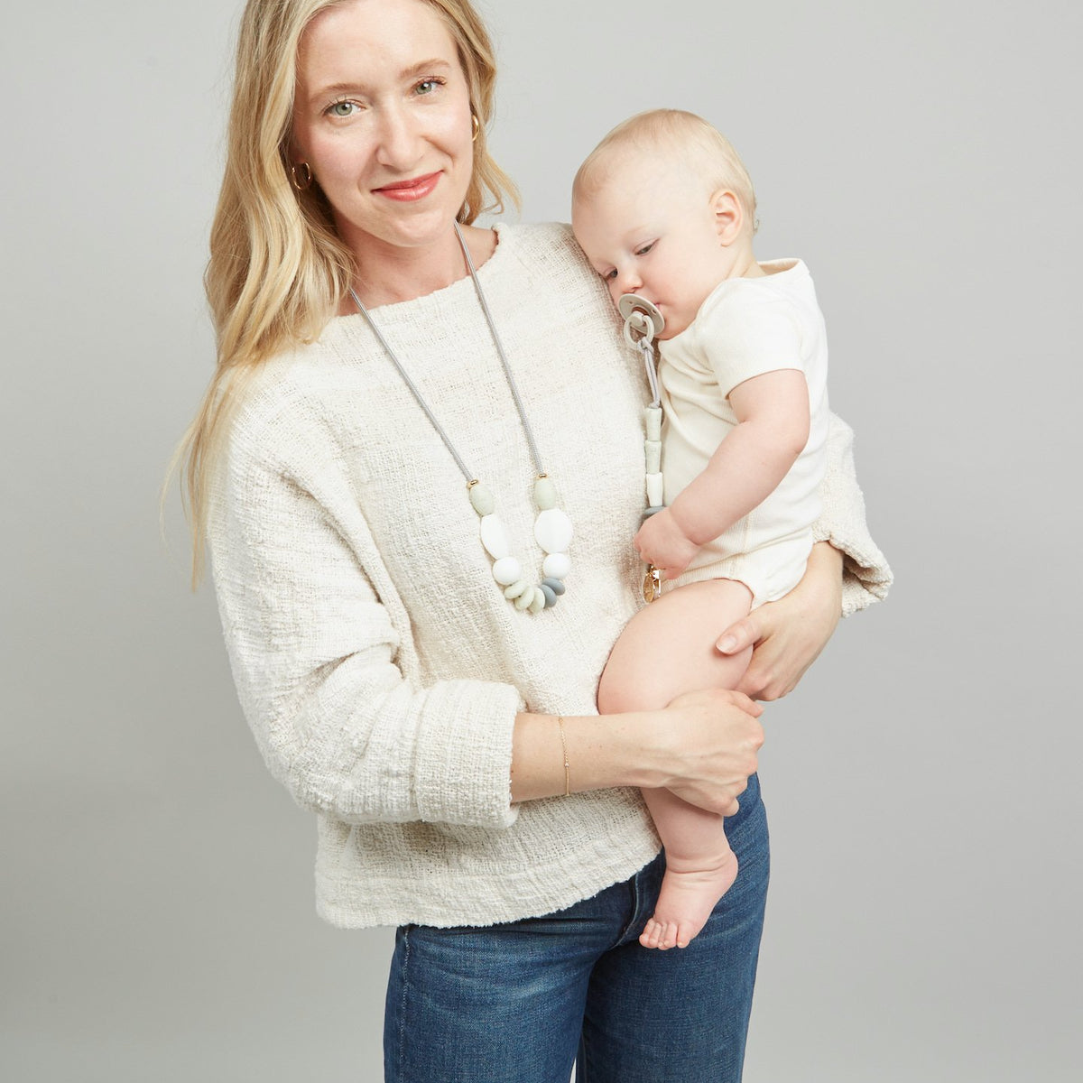 Woman holding a baby against a plain background