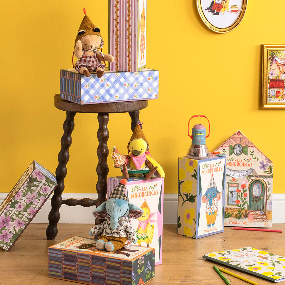 Children's books and toys on a wooden table against a yellow wall with decorative elements.