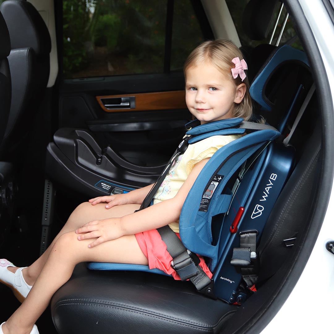 Child in a blue car seat with visible branding inside a vehicle.