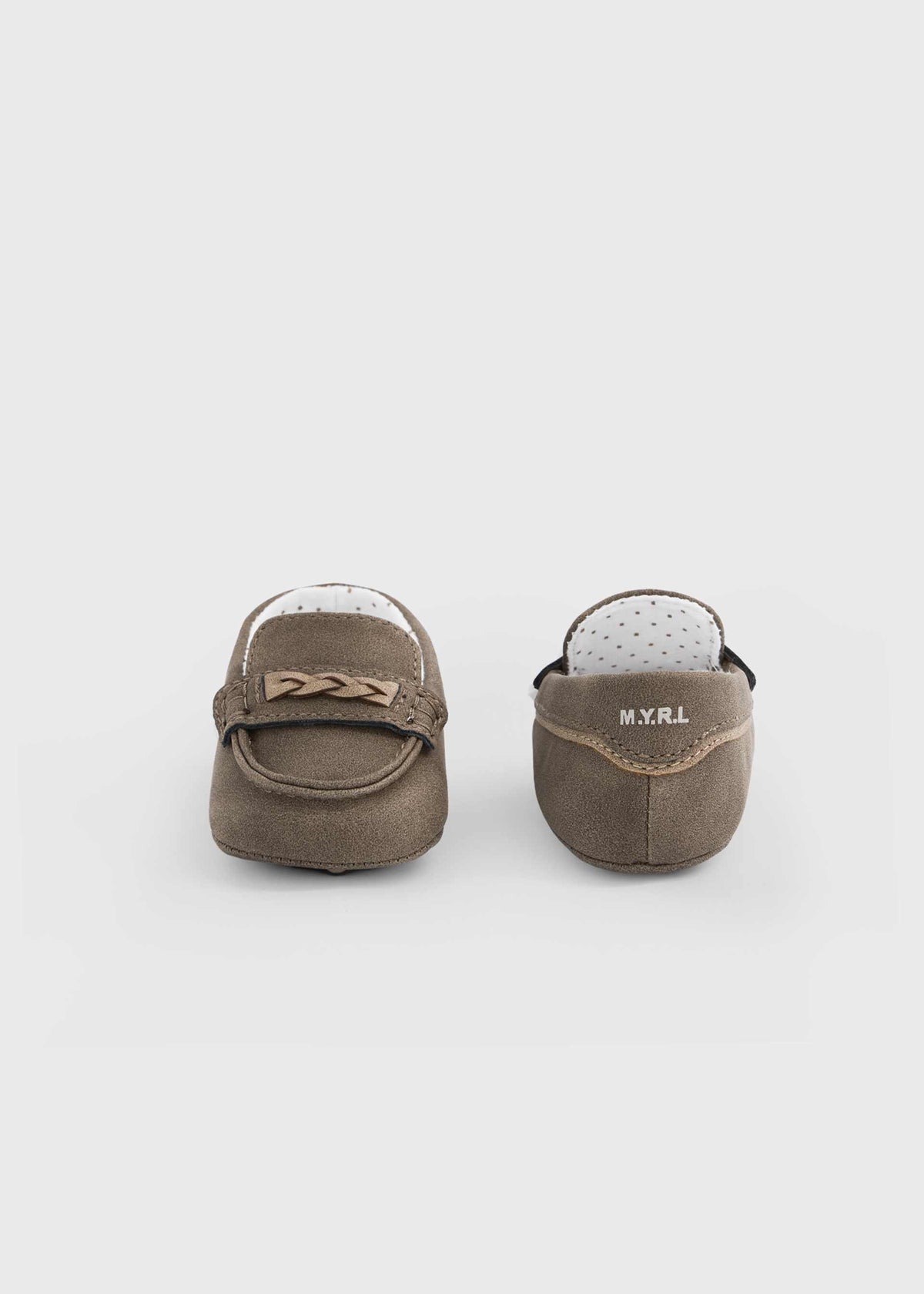 A pair of baby moccasins in taupe brown suede, shown from the back to display the interior. The shoes feature a small decorative bow on the side and the brand name 'M.