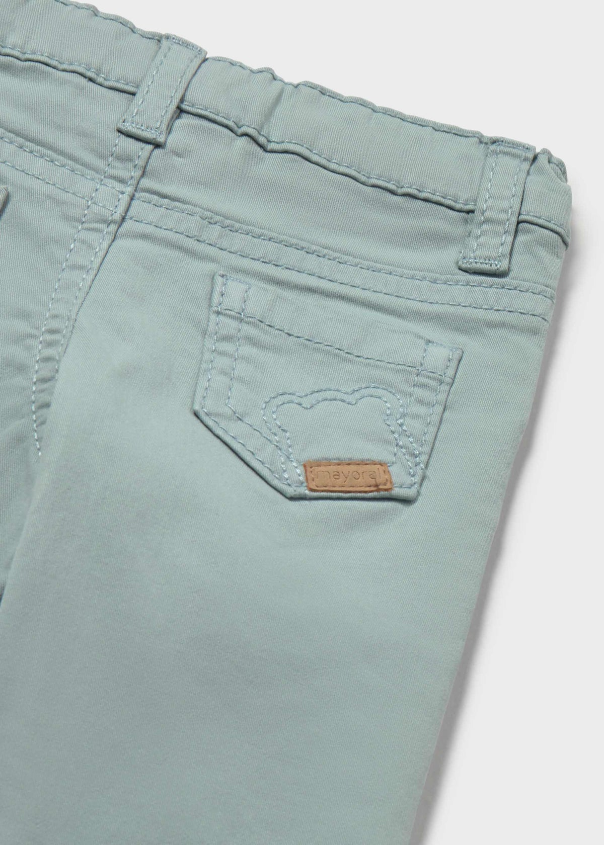 Close-up of a pair of light mint green denim jeans showing the back pocket with a small brown leather brand patch.