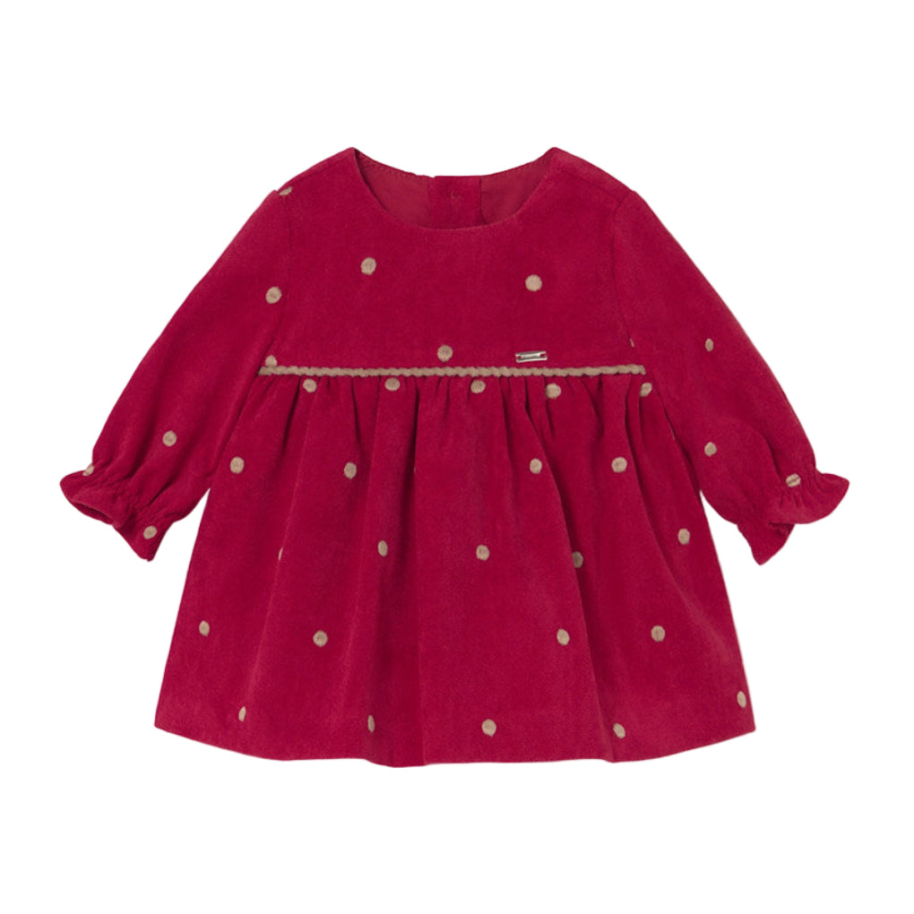 A long-sleeve baby dress in deep magenta corduroy with small beige polka dots and a beige braided trim across the chest, shown flat on a white background.
