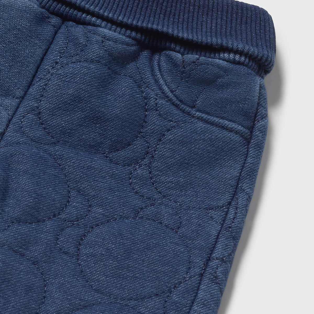 Close-up of blue textured fabric with a pattern on a light gray background