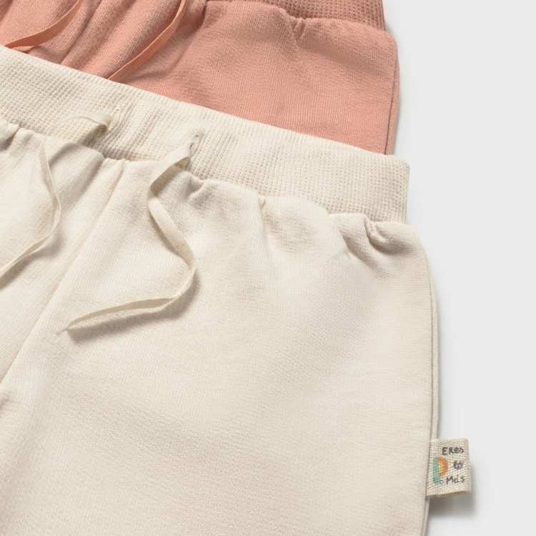 Two pairs of pants, one pink and one beige, on a light gray background.