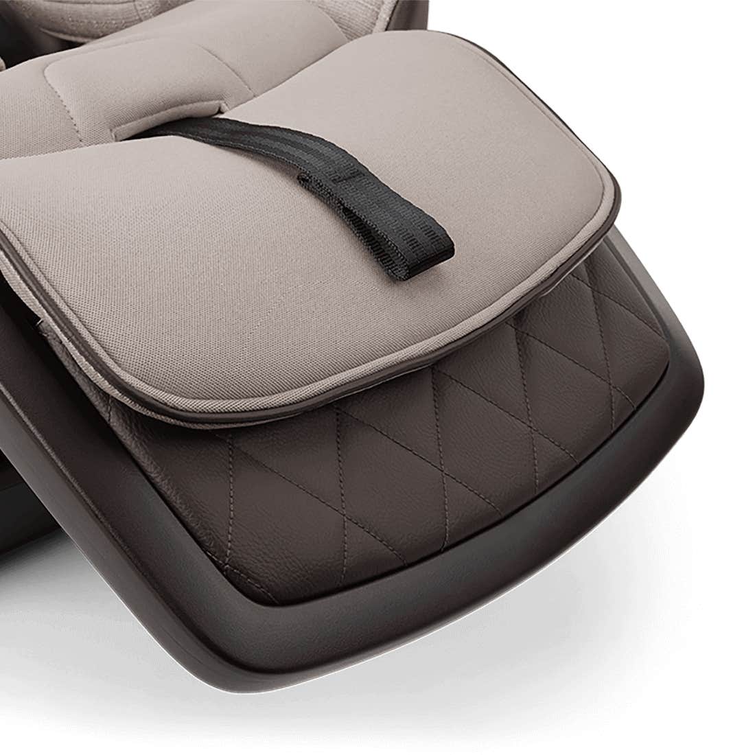 Close-up of a car seat with quilted design and black strap on a white background