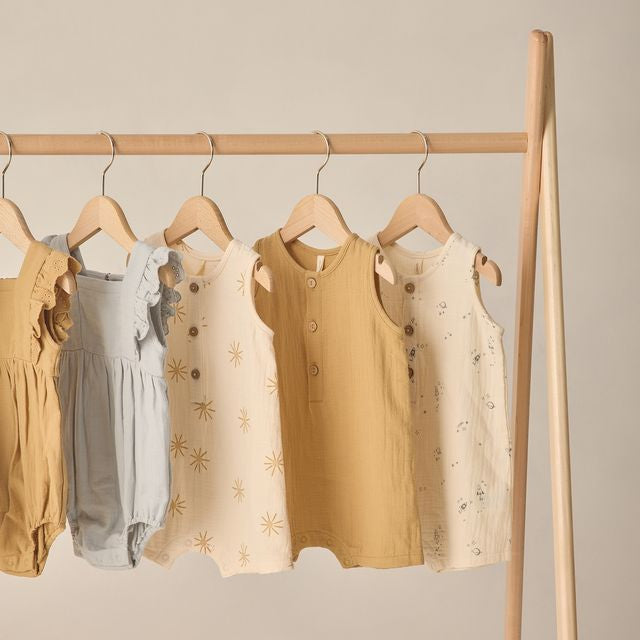 Children's clothing on hangers against a beige wall