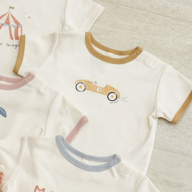 Children's clothing with cartoon designs and text on a neutral background