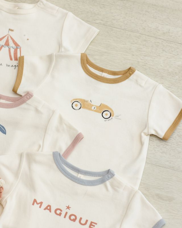 Children's clothing with cartoon designs and text on a neutral background