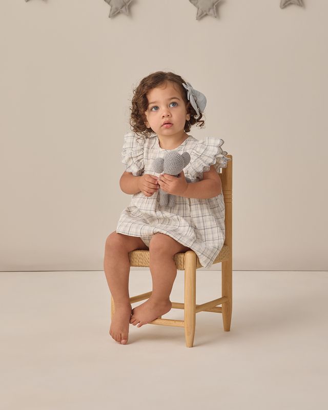 Child sitting on a chair holding toy microphone against a neutral background