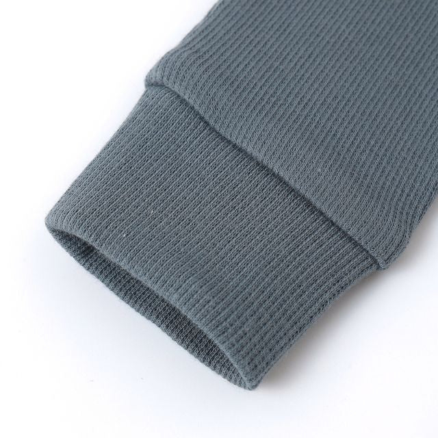 Close-up of a ribbed gray sweater sleeve on a white background