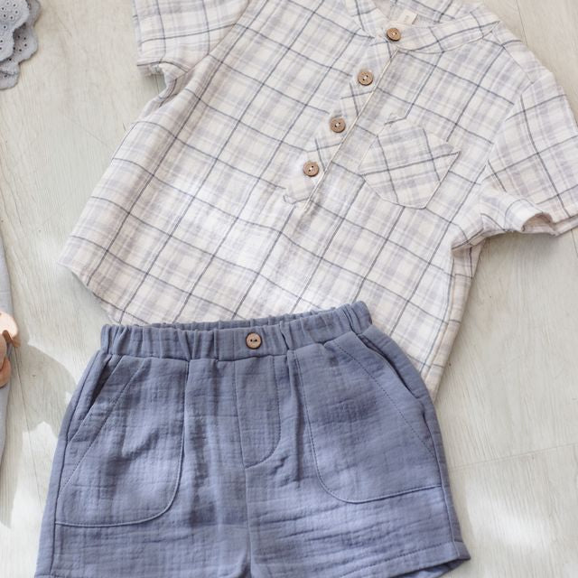 Plaid shirt and blue shorts on a light wooden surface