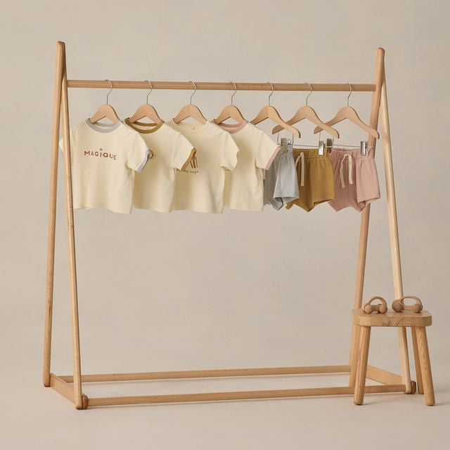 Wooden clothing rack with baby clothes on a beige background