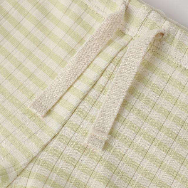 Green and white checkered fabric with a folded edge on a light gray background