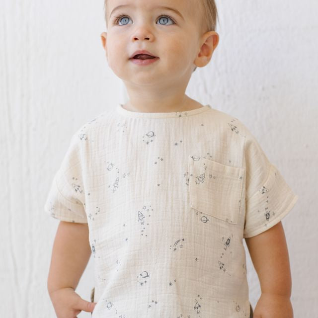 Baby wearing a light-colored shirt with subtle patterns against a white background