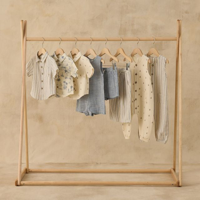 Wooden clothing rack with baby clothes on a beige background
