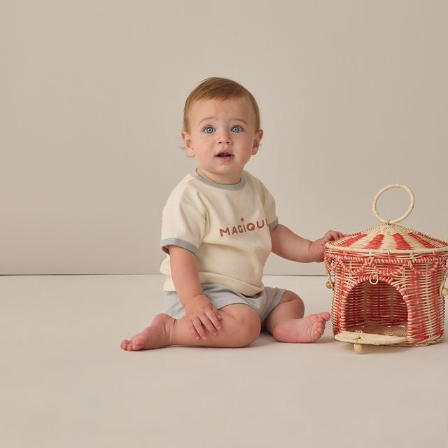 Baby sitting on a plain surface next to a decorative basket