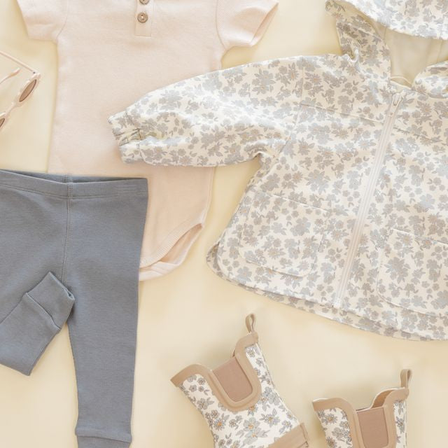 Baby clothing including a shirt, pants, and shoes on a neutral background
