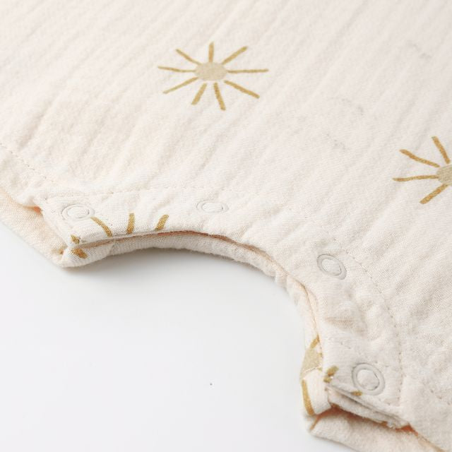 Beige baby romper with gold star patterns on a white background