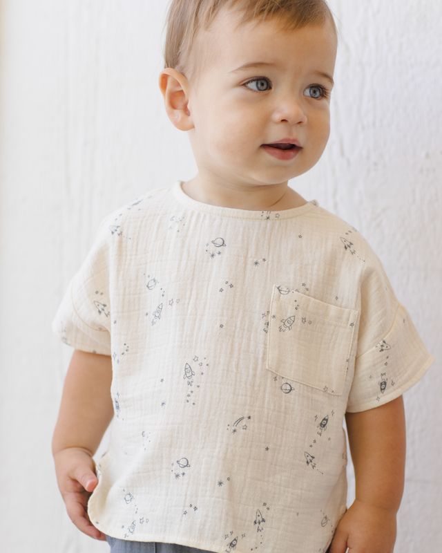 Child wearing a beige short-sleeve shirt with subtle patterns on a plain background
