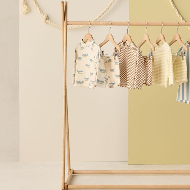Children's clothing on a wooden rack against a light background