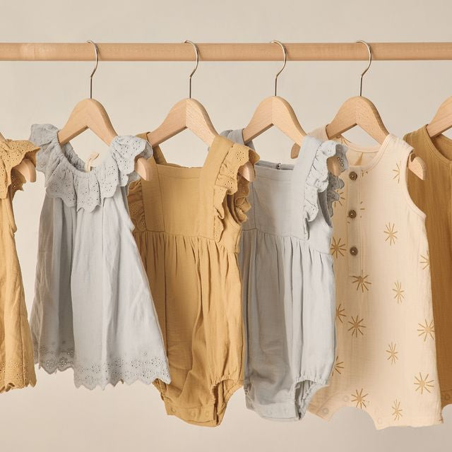 Children's clothing on hangers against a neutral background