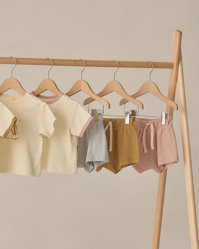 Children's clothing on hangers against a beige wall