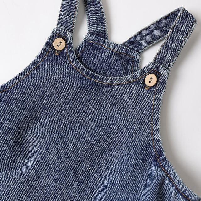 Close-up of a blue denim overall with button details on a white background