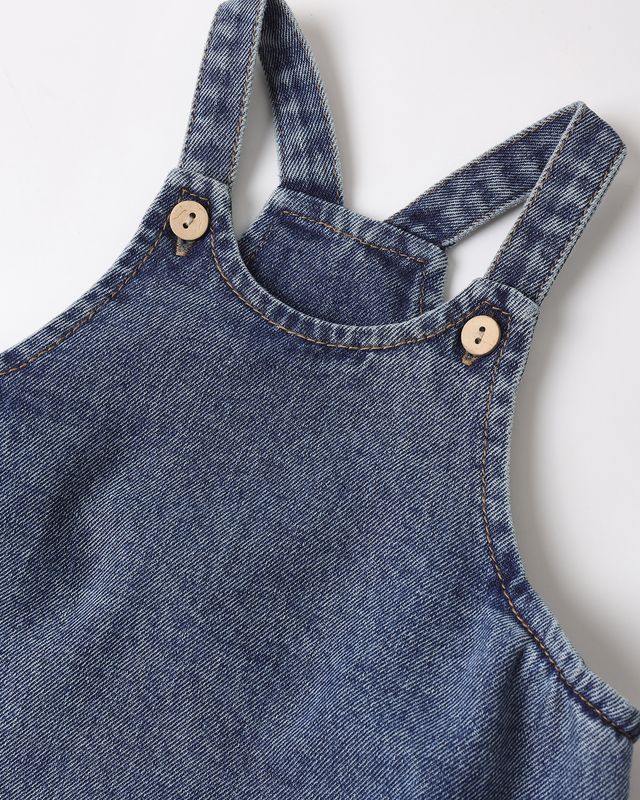 Close-up of a blue denim overall with button details on a white background