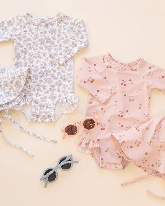 Children's floral dress and swimsuit with sunglasses on a light background