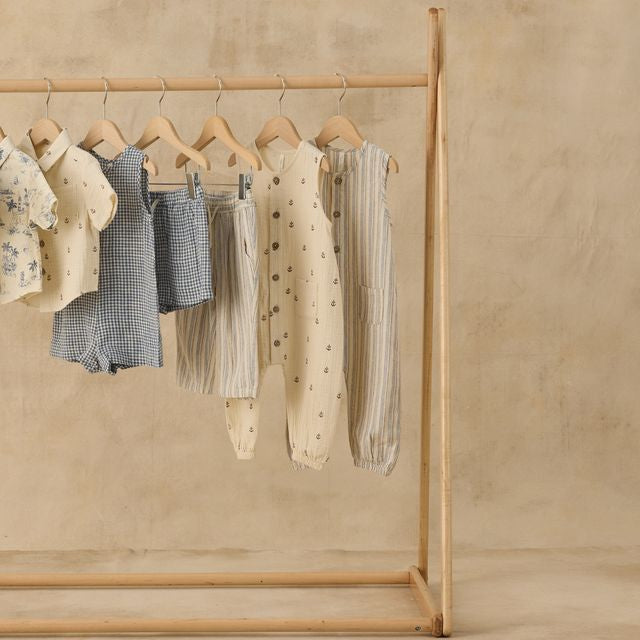 Wooden clothing rack with baby clothes on a beige background