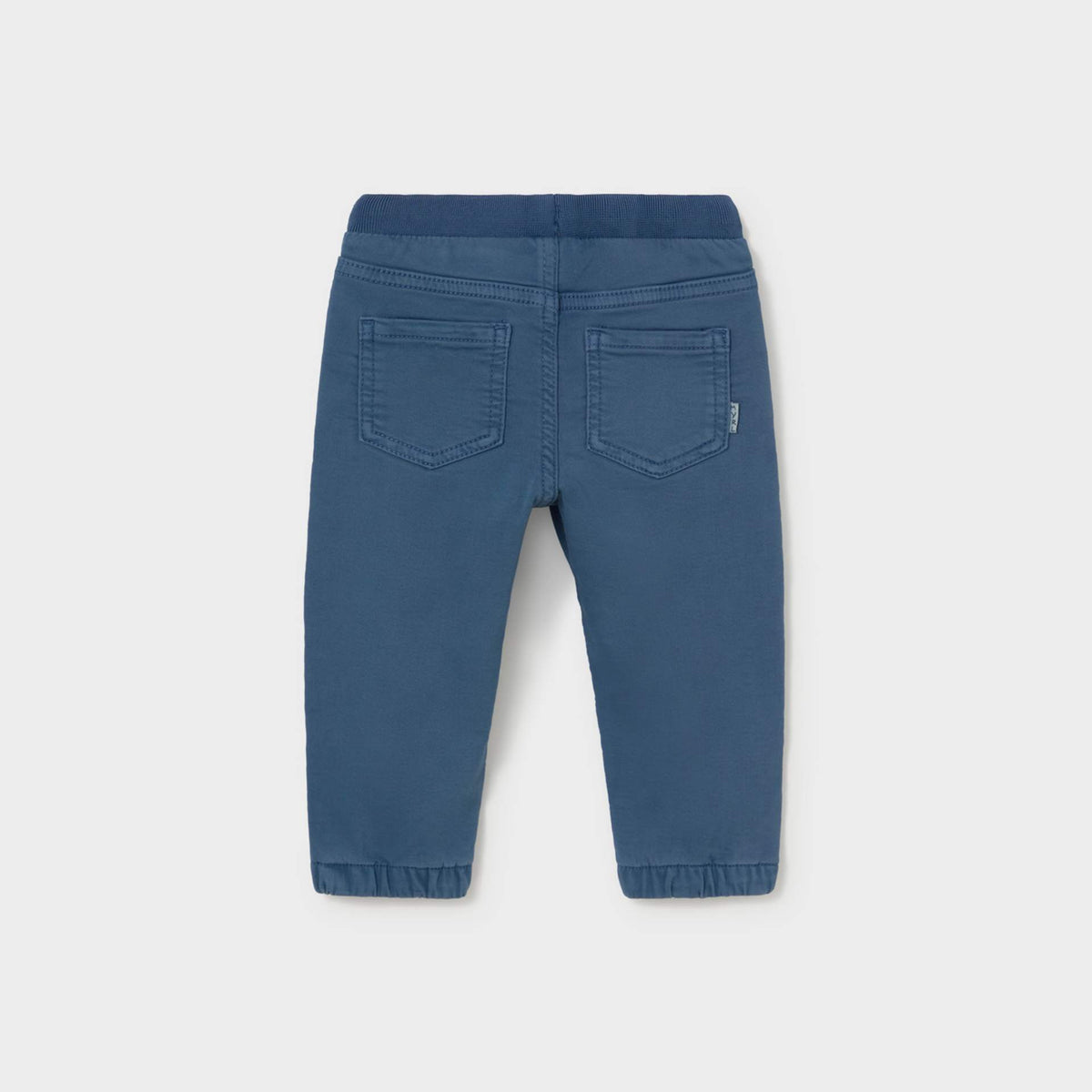 Blue denim pants shown from the back, featuring a wide elastic waistband, two back patch pockets, and elastic cuffs at the ankles, photographed on a light gray background.