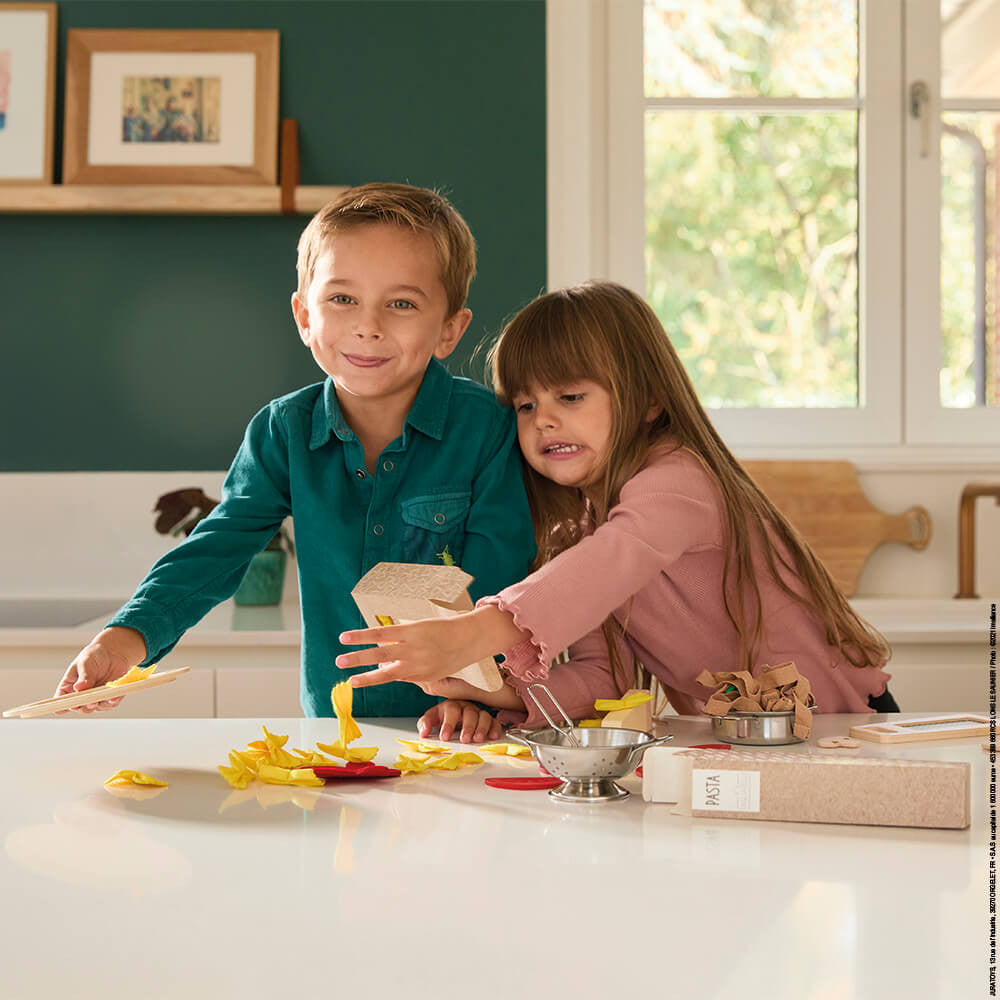 Two children in a kitchen preparing food on a counter.