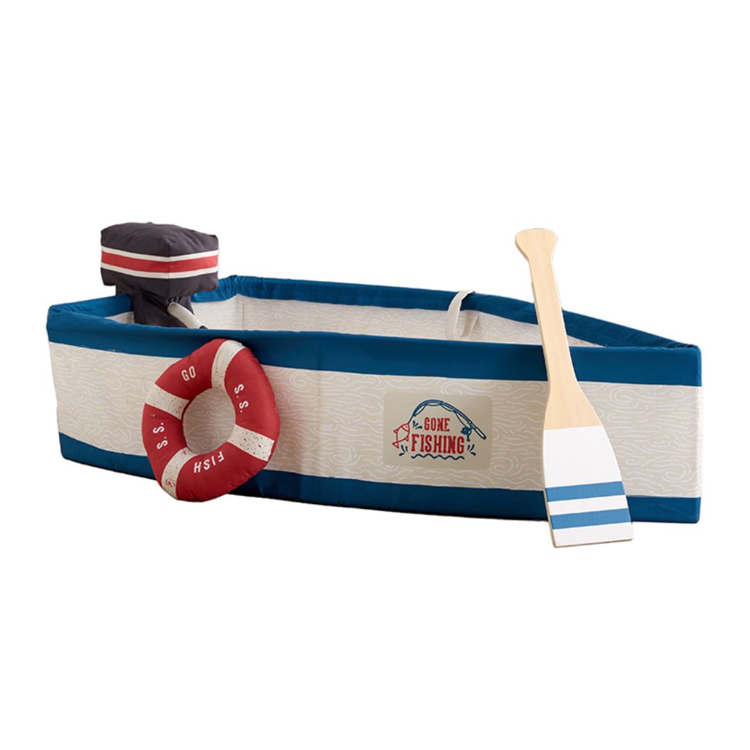 A children's nautical-themed play boat set on a white background, featuring a fabric boat with blue and cream stripes, a red life preserver, a wooden paddle, and a small black motor attachment.