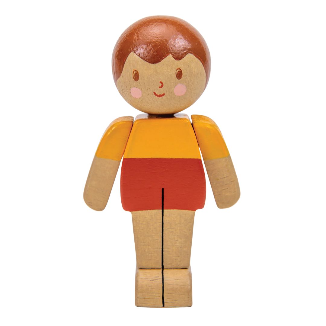 A wooden toy figure with a round head, brown hair, a yellow-orange shirt, and red shorts, shown on a plain white background.