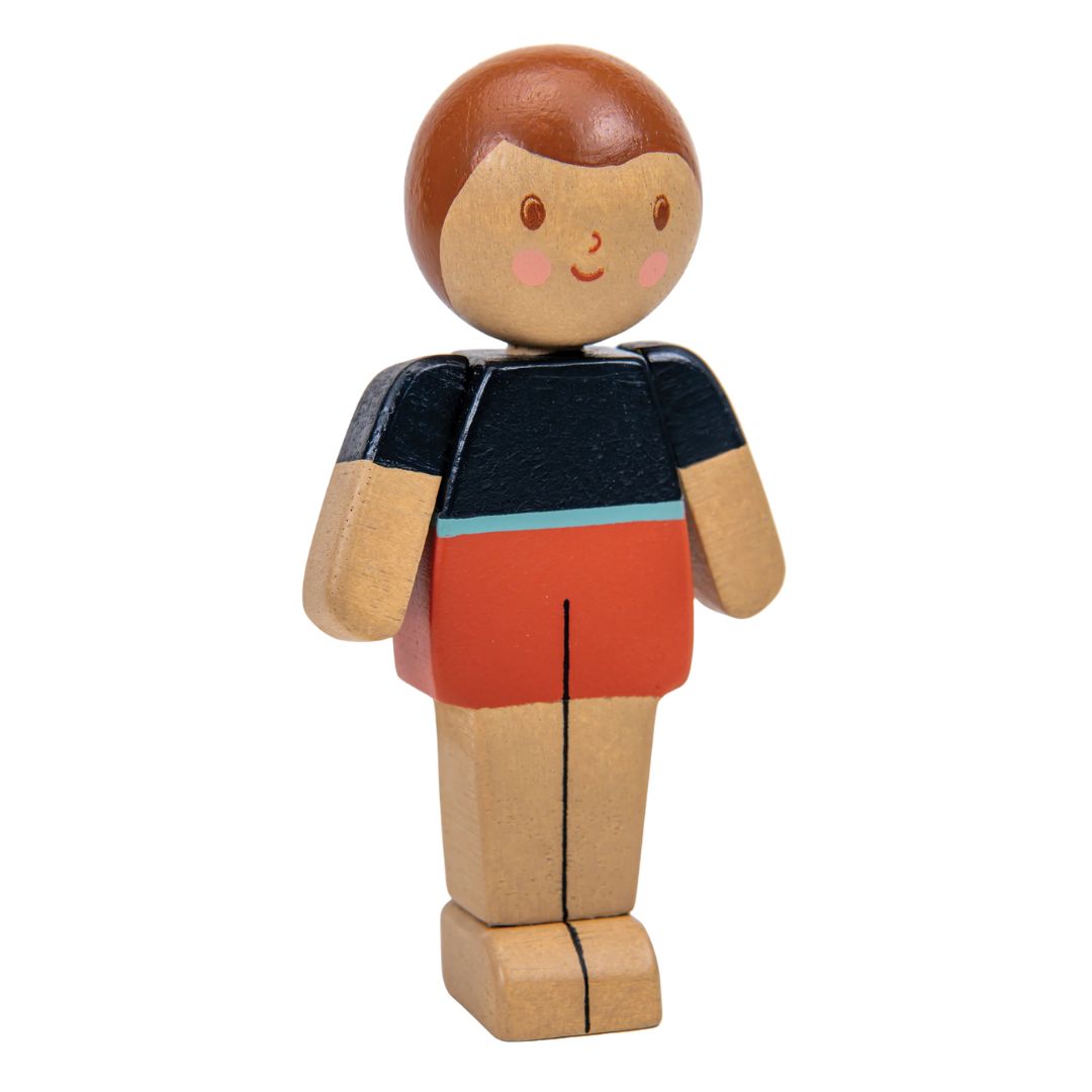 Wooden toy figure of a person with a black shirt and red shorts on a white background