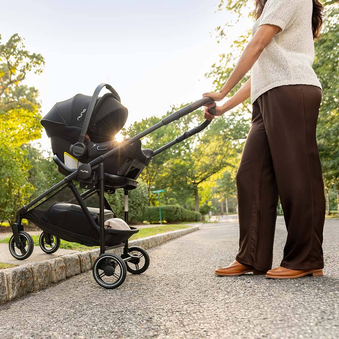 Person pushing a stroller with a baby seat in a park setting