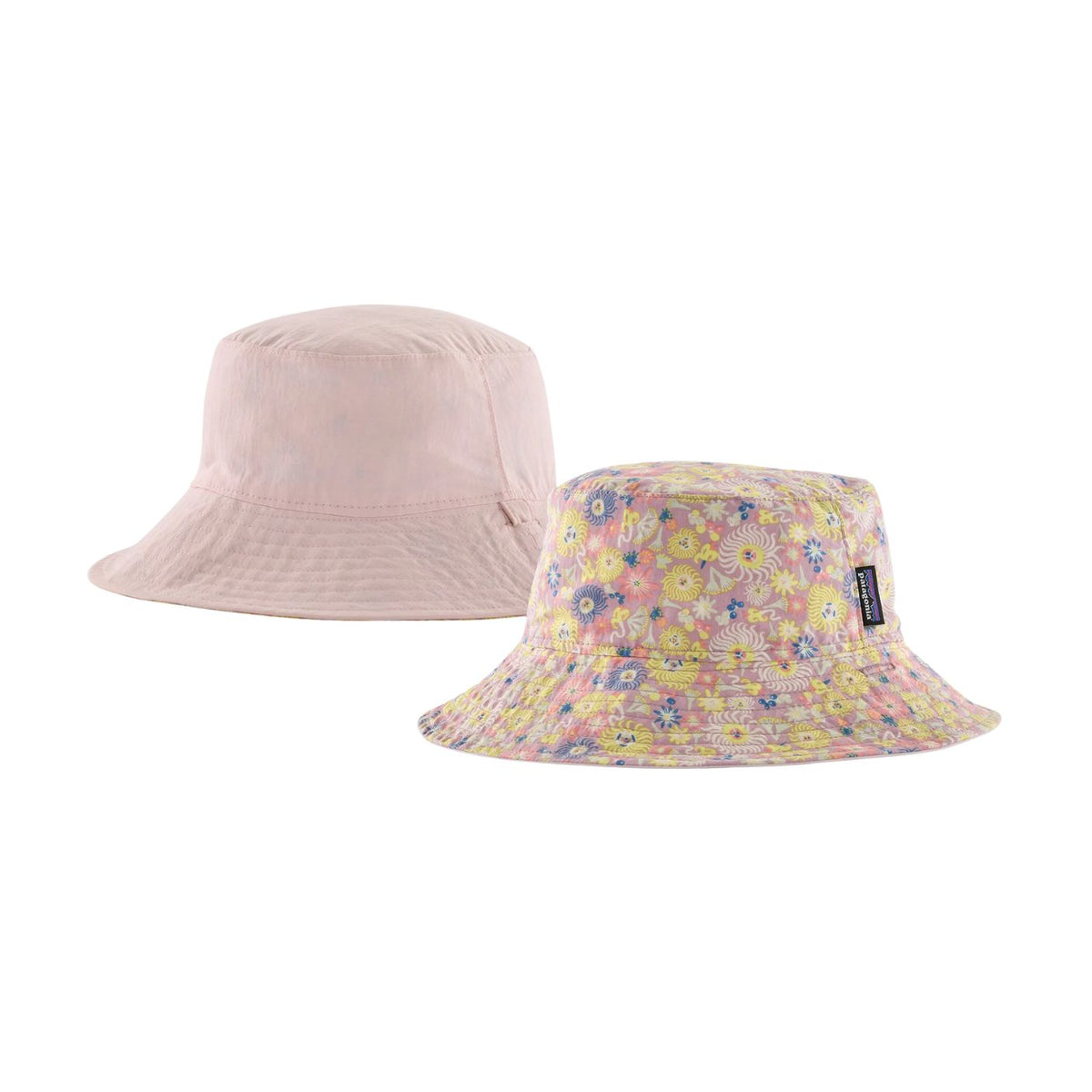 Two bucket hats on a plain white background: one solid pale pink hat in the back and one floral bucket hat in the front with a small black brand tag on the side.
