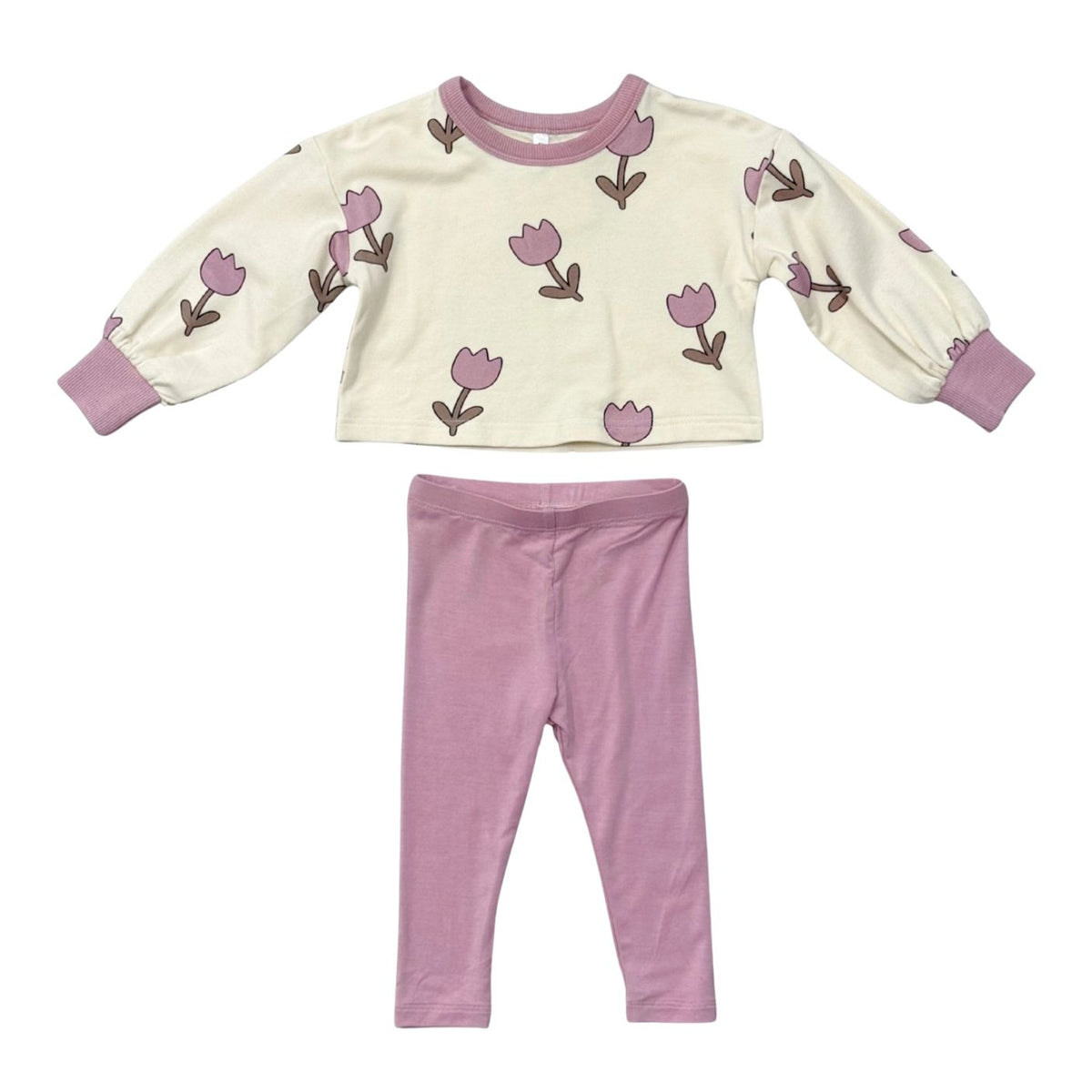 A toddler's two-piece pajama set featuring a cream long-sleeve top with a pink tulip pattern and pink ribbed trim, paired with matching pink leggings, laid flat on a white background.
