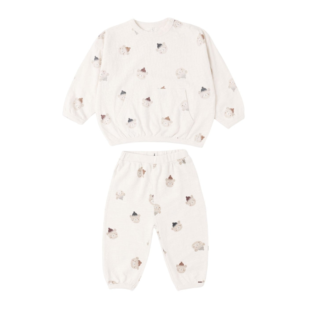 A two-piece baby pajama set featuring a long-sleeve top and matching pants in a warm off-white/cream color, decorated with a scattered print of small teddy bears wearing tiny hats.