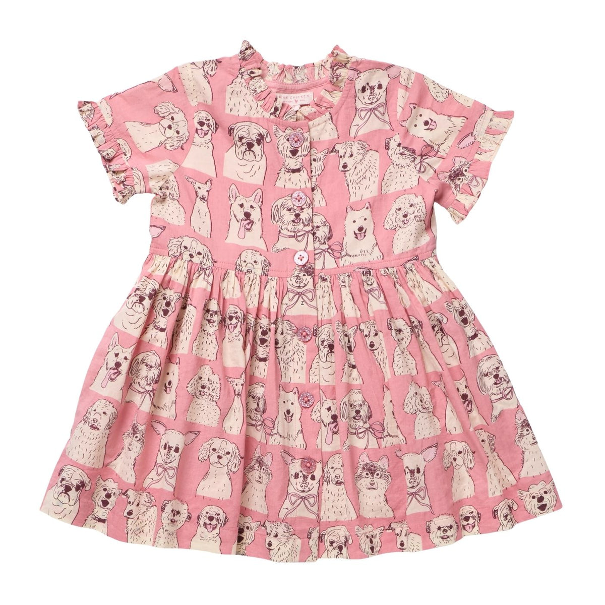 A pink short-sleeve dress for toddlers or girls, featuring an all-over print of poodle illustrations. The dress has a ruffled neckline, short flutter sleeves, a gathered waist, and a button-up front.