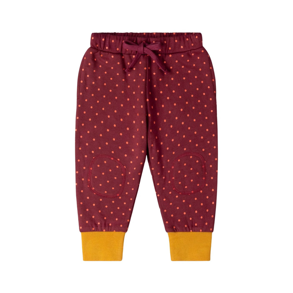 A pair of children's jogger pants in burgundy with a pattern of small orange dots, featuring a matching drawstring waist and contrasting mustard yellow ribbed cuffs.